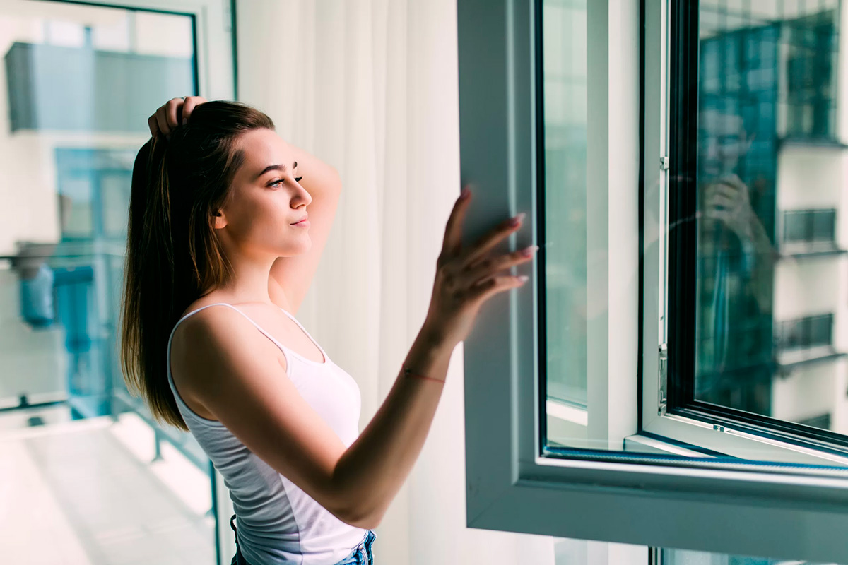 young woman opens plastic window fresh air smiling home scaled 1